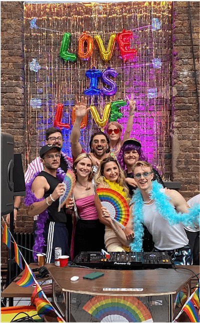 A group photo of eight Lendable employees posing in front of a rainbow 'Love is Love' sign at Lendable's annual Pride Party