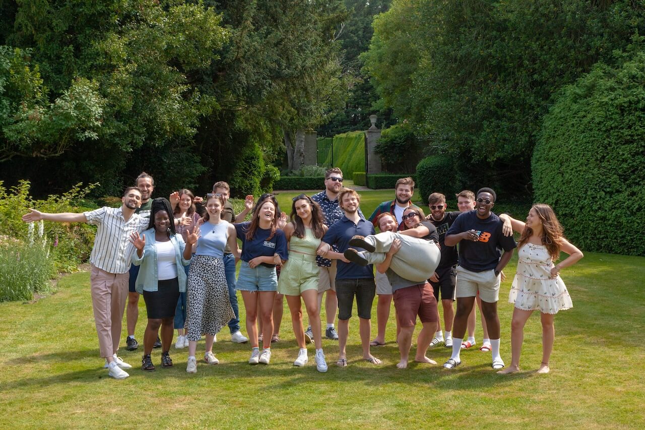 A group photo of the Lendable operations team smiling and waving at the camera in a country garden